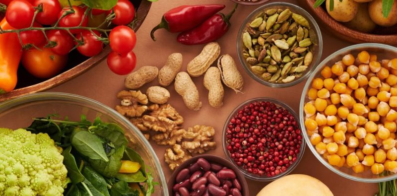 Explore a colorful assortment of healthy ingredients, featuring vegetables, nuts, seeds, and spices in a top view layout.