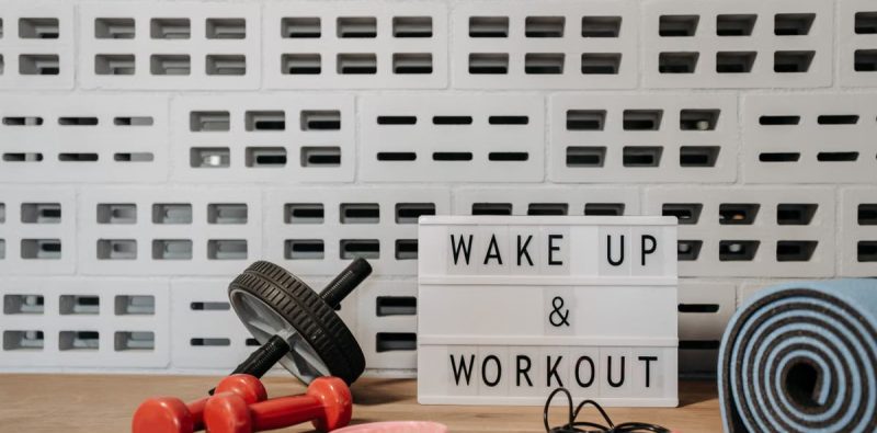 Fitness gear and motivational sign in home gym setup against a brick wall.